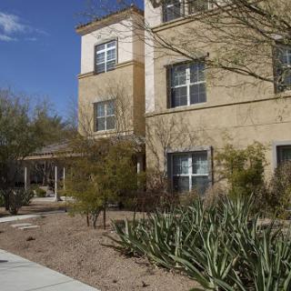 A modern residential building surrounded by a landscaped garden.