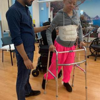 A caregiver assists a patient using a walker during rehabilitation.