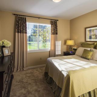 A well-decorated bedroom with a large window allowing natural light, complete with a cozy bed and stylish furnishings.