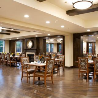 A cozy dining room with wooden flooring and well-arranged tables and chairs.