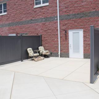 A small patio area with two chairs, surrounded by a brick building and privacy fencing.