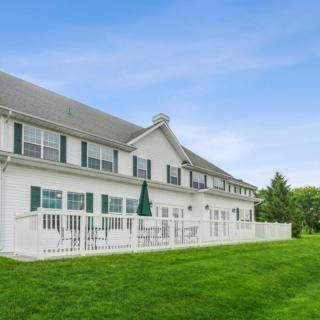A large, white residential building with a green lawn and clear sky.