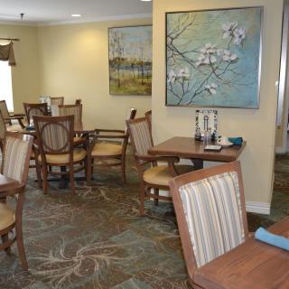 A cozy dining room with wooden tables and chairs, decorated with paintings on the walls.