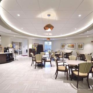 A modern dining area with arranged tables and chairs, featuring overhead lighting.