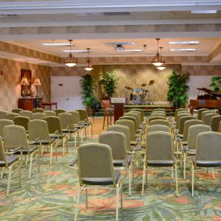 An empty conference room arranged for a presentation or lecture, with rows of chairs facing a podium.