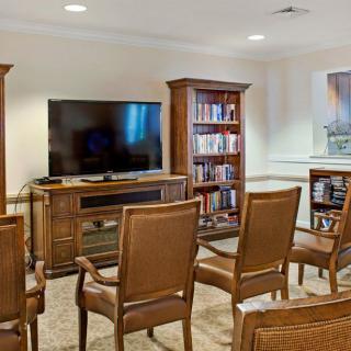 A cozy living room setup with a television, wooden chairs, and bookshelves.