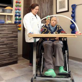 A doctor assists an elderly person in a wheelchair at a healthcare facility.