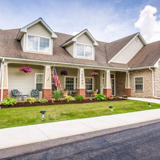 A charming two-story suburban house with a well-maintained lawn and front porch.