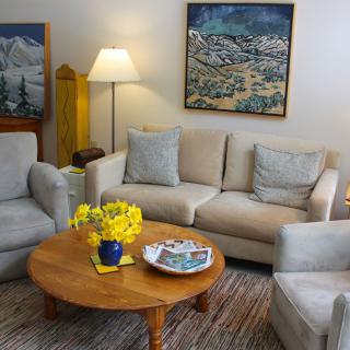 Cozy living room with a sofa, armchairs, and a coffee table adorned with yellow flowers.