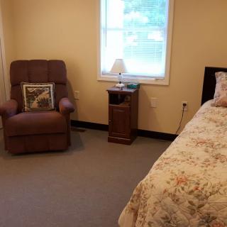 Cozy bedroom with a recliner chair, bedside table, and a window.