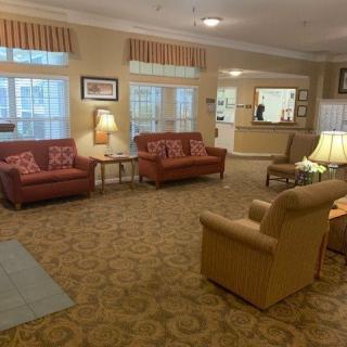 A cozy living room with sofas, chairs, and warm lighting.
