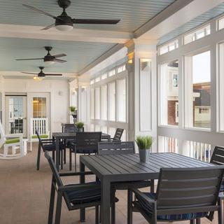 A modern outdoor patio dining area with tables and ceiling fans.