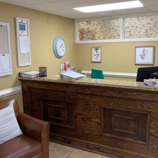A cozy office reception area with a wooden desk and comfortable seating.