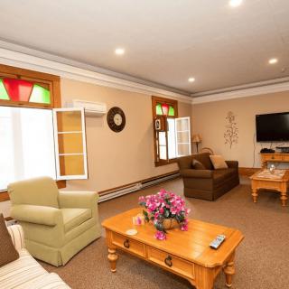 A cozy living room featuring comfortable seating, a wooden coffee table with a floral centerpiece, and a wall-mounted television.