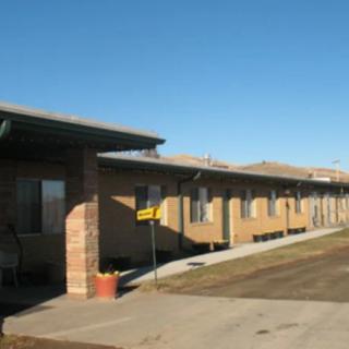 A single-story motel building with a brick exterior under a clear blue sky.