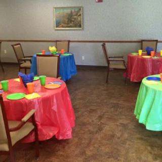 A room is set up with colorful tables and chairs, ready for a party or event.