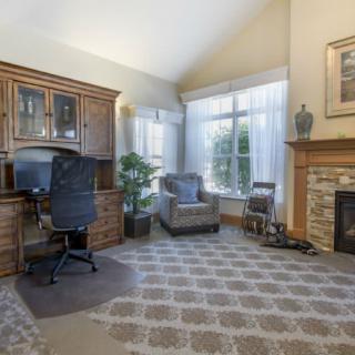 A cozy home office space with a desk, chair, armchair, and fireplace.