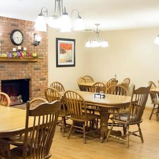 A cozy dining room with wooden tables and chairs, featuring a brick fireplace.