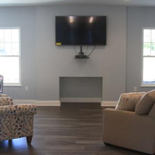 A cozy living room with a mounted television and comfortable seating.