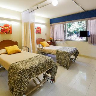 A hospital room with two beds, curtains, and a window providing natural light.