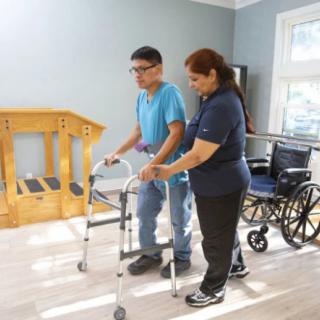 A therapist assists a patient using a walker for rehabilitation exercises.