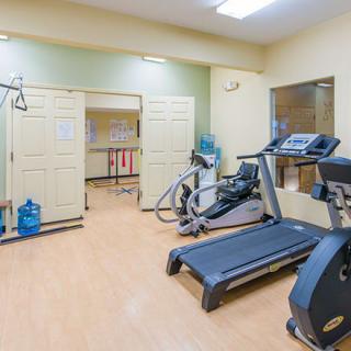 A small gym with exercise equipment including a treadmill and an elliptical machine.