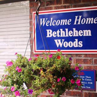 A welcoming sign at Bethlehem Woods with a colorful hanging flower basket.