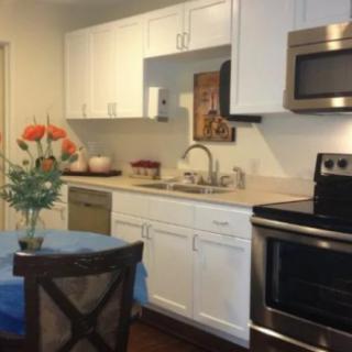 A modern kitchen with white cabinets, stainless steel appliances, and a dining table with flowers.