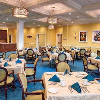 An elegant dining room with neatly arranged tables and chairs, featuring a warm color scheme.