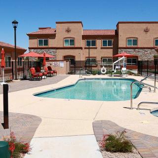 An outdoor swimming pool area at a hotel, featuring umbrellas and lounge chairs under a clear blue sky.