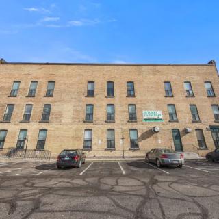 A brick building with multiple windows and a parking lot in front.