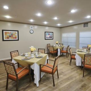 A well-lit dining area with neatly arranged tables and chairs, featuring decorative art on the walls.