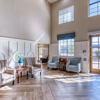 A modern living space with ample natural light, featuring elegant furniture and wood flooring.