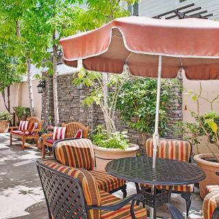 A cozy outdoor patio with striped furniture and an umbrella providing shade.