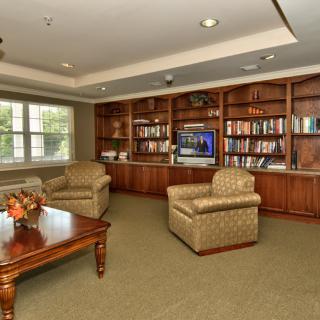 A cozy living room with a library, featuring bookshelves, armchairs, and a coffee table.