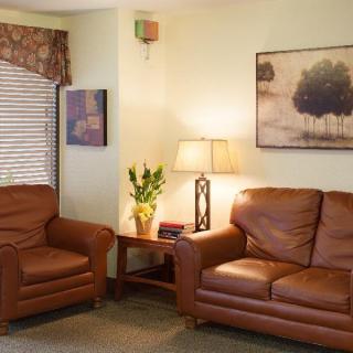 A cozy living room with leather sofas, a lamp, and framed artwork on the walls.