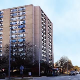 A tall residential apartment building nestled in an urban setting.