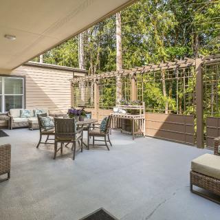 A spacious outdoor patio with comfortable seating and a wooded backdrop.