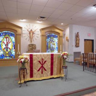 Interior view of a church featuring a decorated altar and beautiful stained glass windows.