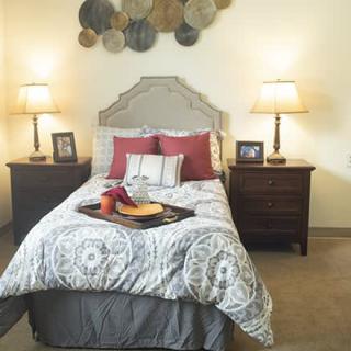 A cozy bedroom with a neatly made bed, flanked by two nightstands and lamps.