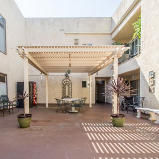 A spacious courtyard featuring a pergola with outdoor seating and potted plants.