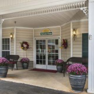 A welcoming hotel entrance adorned with floral arrangements and benches.