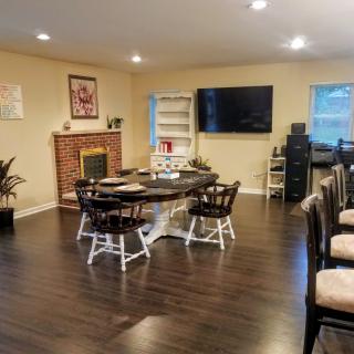 A cozy living room with a dining area, featuring a fireplace, television, and hardwood flooring.