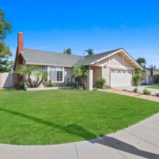 A suburban house with a well-maintained lawn and garage on a clear day.