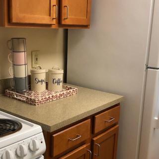 Cozy kitchen corner with wooden cabinets, a stove, and decorative canisters on the countertop.