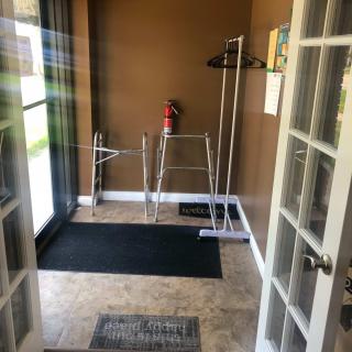 Entryway with walkers and a coat rack near glass doors.
