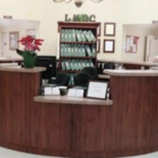 A reception desk with a wooden counter and shelves, decorated with plants.