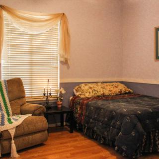 Cozy bedroom with a bed, armchair, and window with curtains.