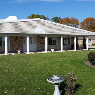 A single-story house with a front porch featuring columns and a well-maintained lawn.