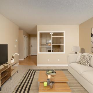 A cozy living room featuring a comfortable sofa, wooden coffee table, and a TV stand, complemented by a stylish rug and neutral wall colors.